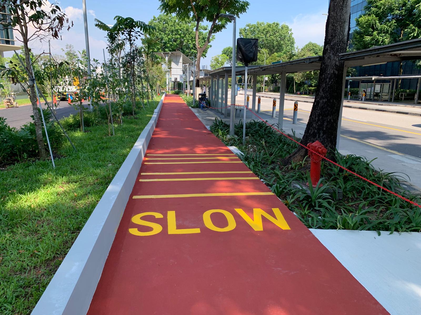 Red-coated cycling and pedestrian path with SLOW lettering and yellow lane markings by EMK Construction